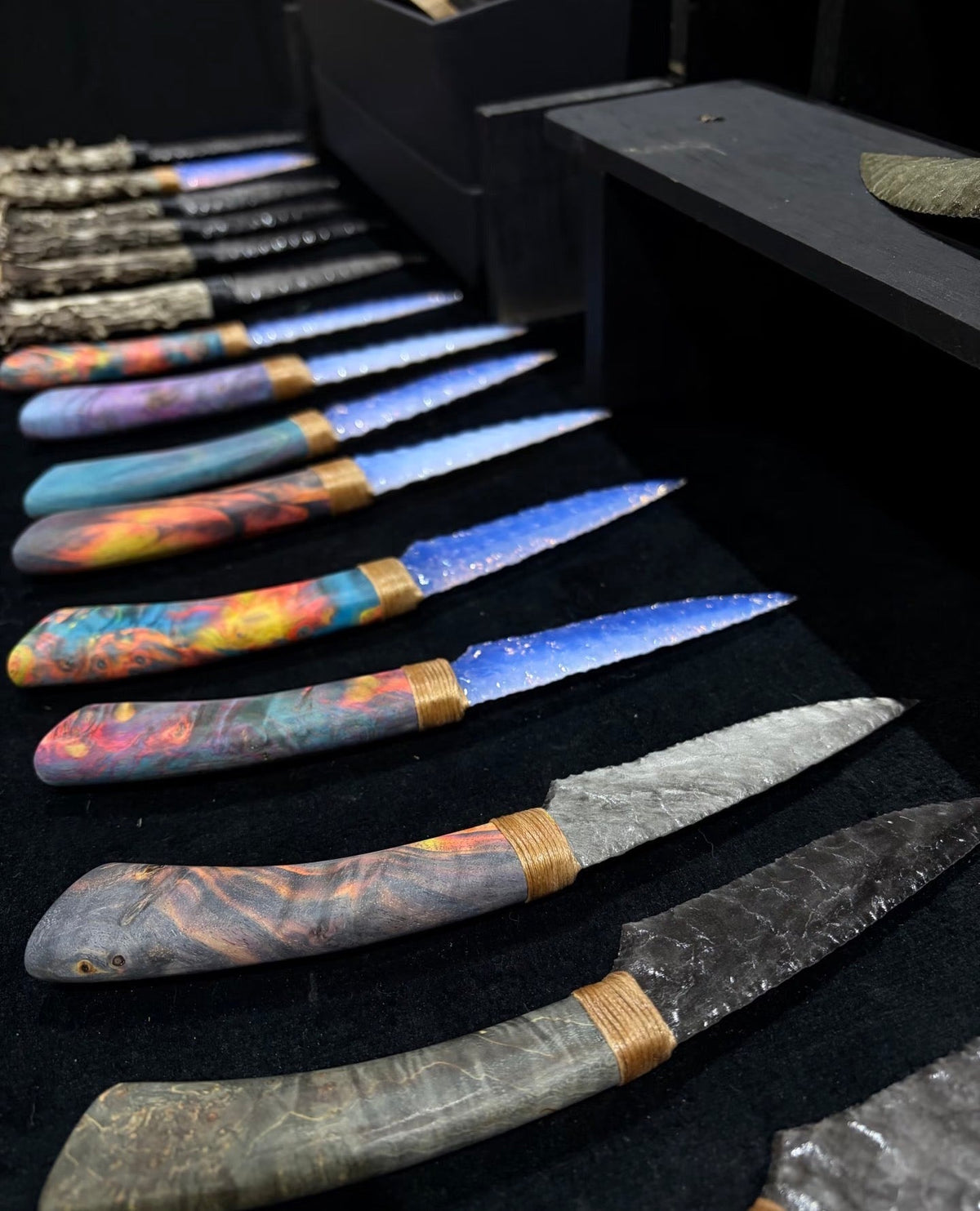 A selection of colorful handcrafted RELIQ display blades arranged at a craft exhibition