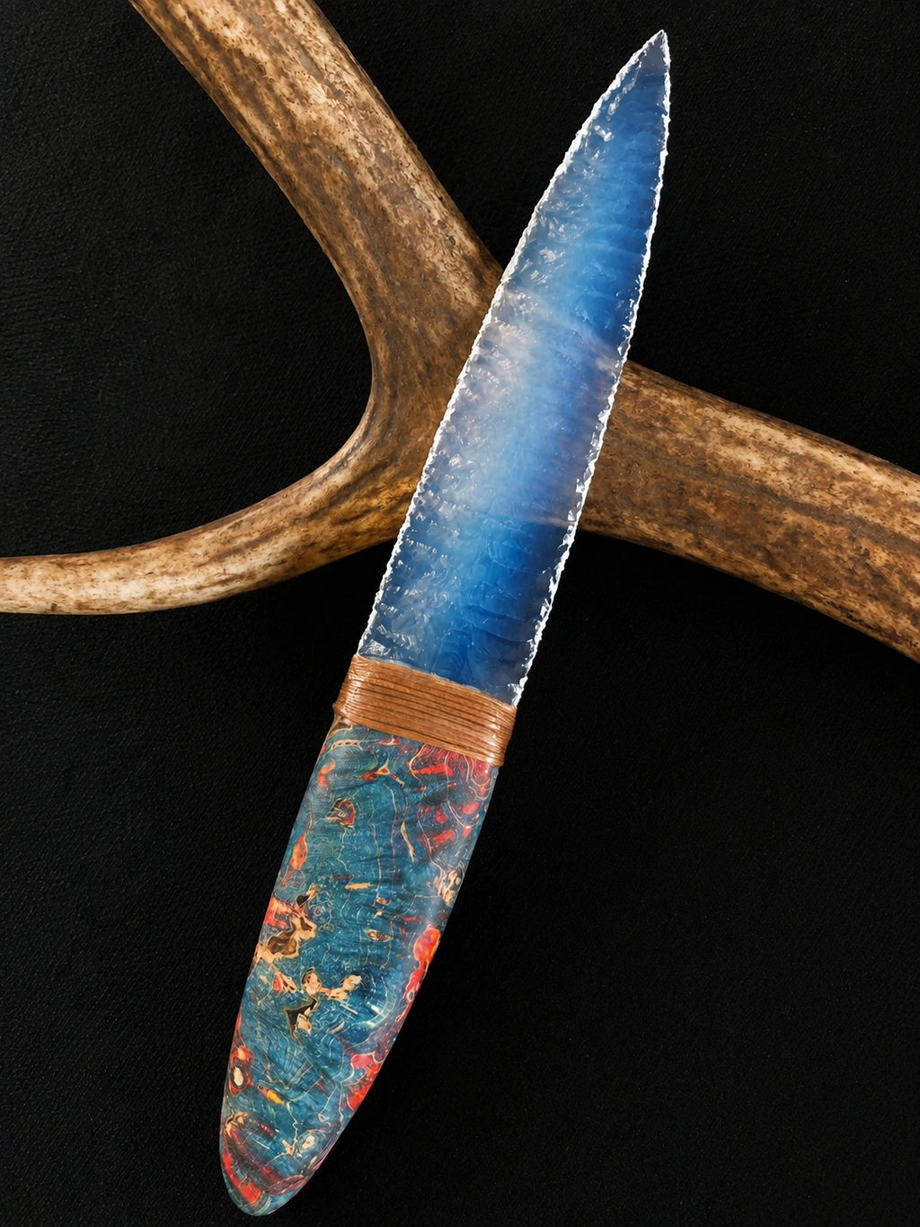 Blue broad-blade display knife photographed against antler-style decor