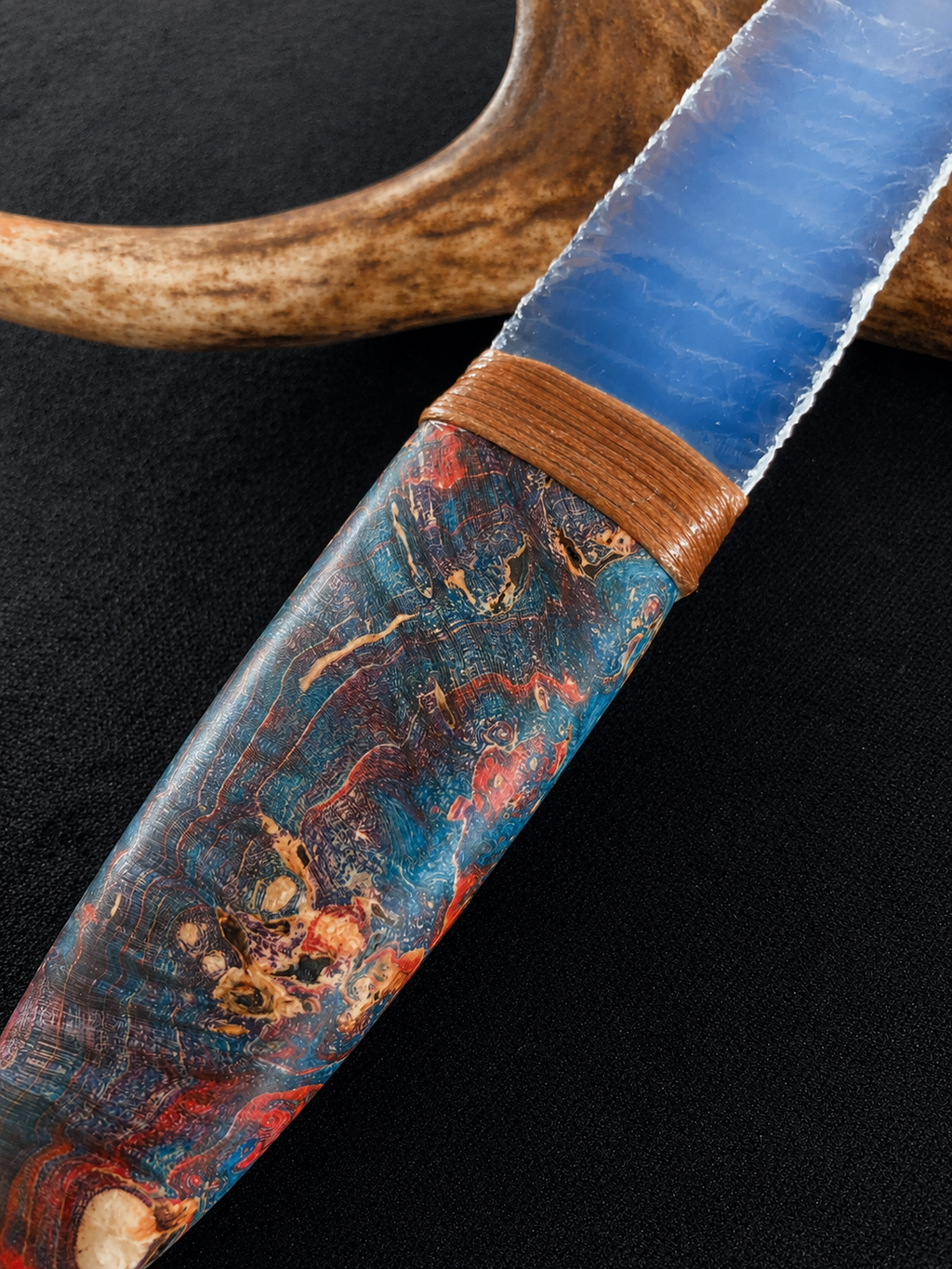Close-up of a blue knapped blade and colorful handle