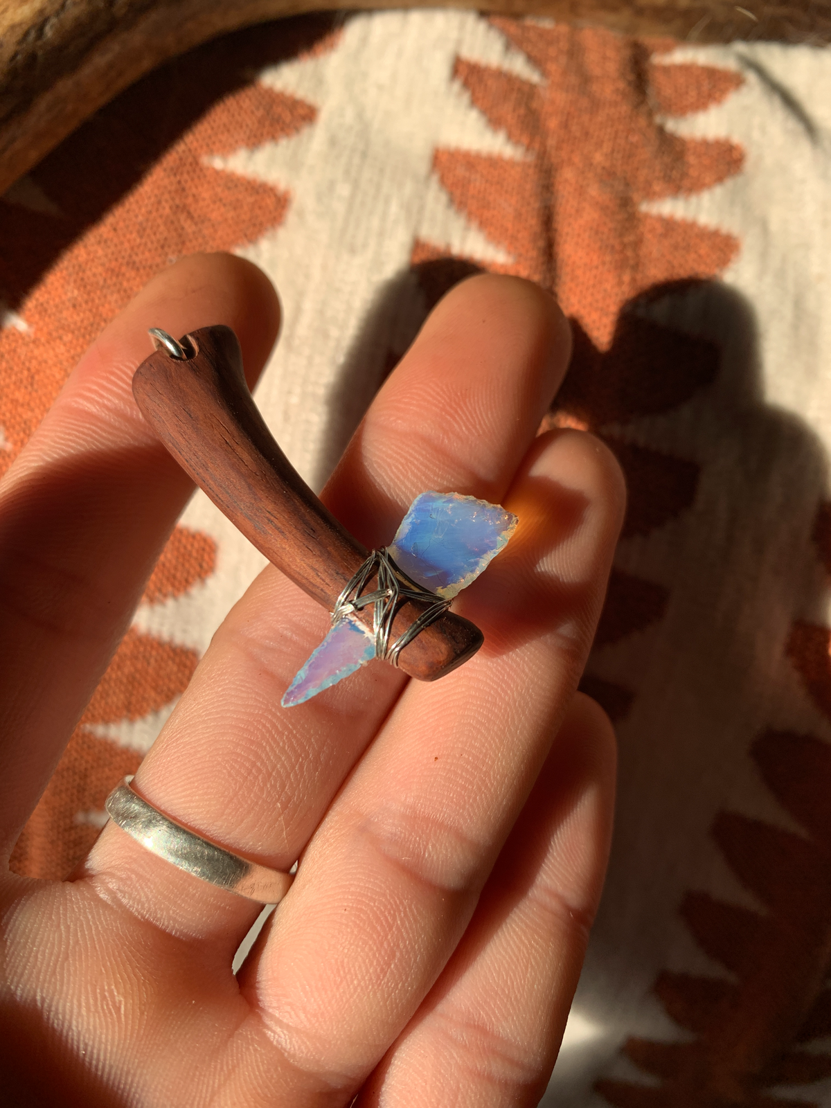 Opalescent blue miniature axe pendant shown in hand