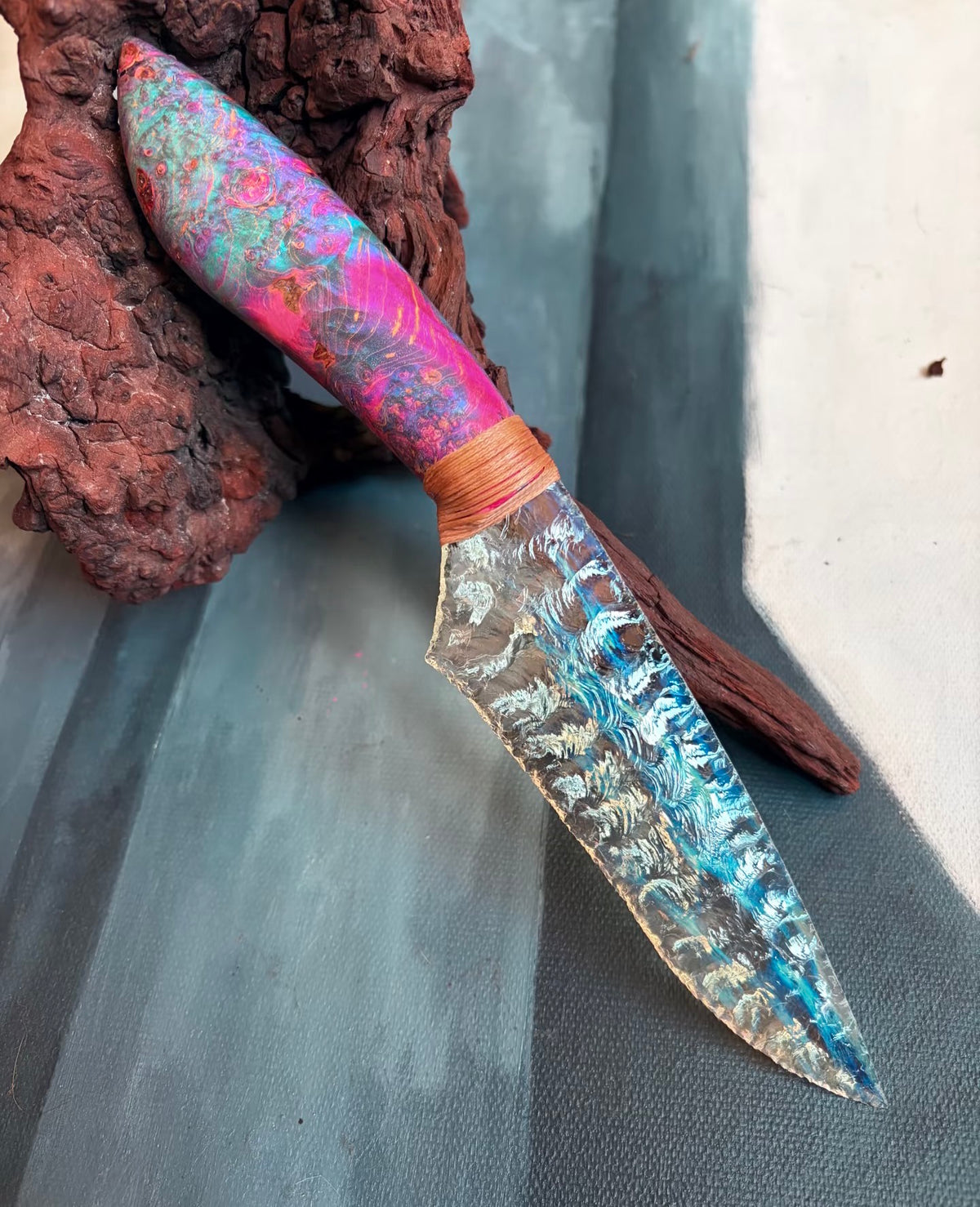 Transparent blue knapped display knife photographed on a dark wooden surface